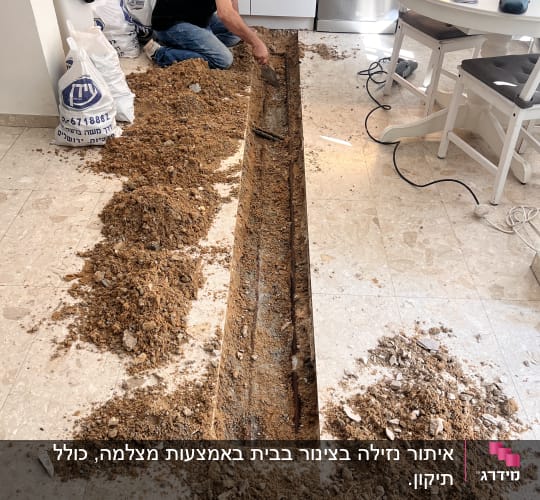 אדם עובד על תיקון צנרת במטבח עם כלים וחול